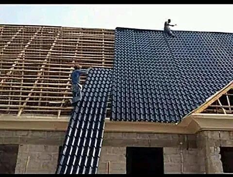 Installers fitting a dark stone-coated roof