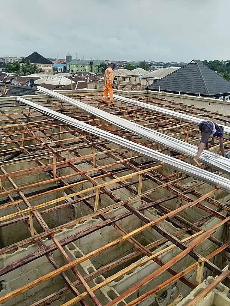 Workers installing purlins, warehouse roof frame